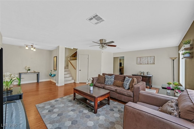 living room with stairway, wood finished floors, ceiling fan, baseboards, and visible vents