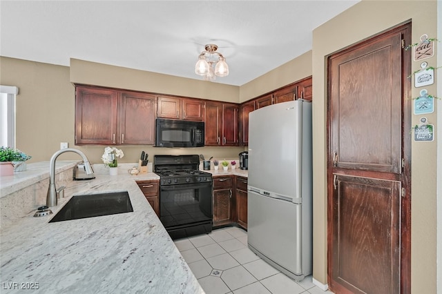 kitchen featuring light stone counters, a sink, black appliances, light tile patterned floors, and a peninsula