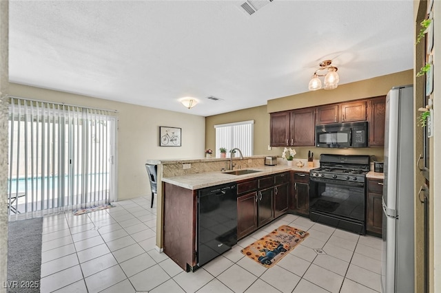 kitchen featuring a peninsula, visible vents, a sink, and black appliances