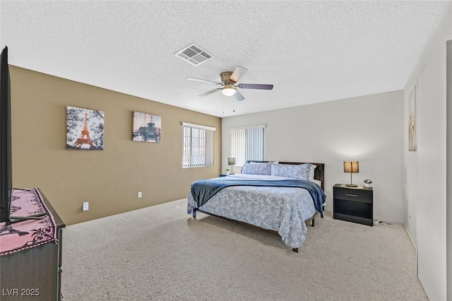 bedroom with a textured ceiling, carpet floors, visible vents, and a ceiling fan