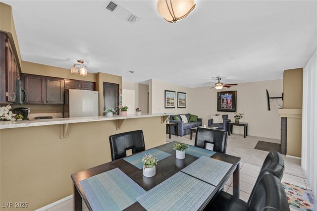 dining space with ceiling fan, light carpet, and visible vents