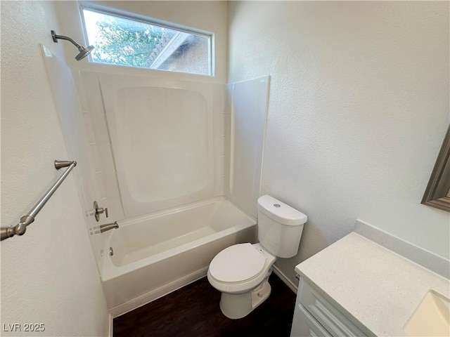 full bathroom featuring vanity, toilet, a textured wall, and shower / washtub combination