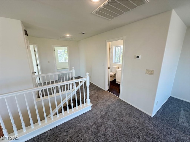 hall with baseboards, carpet flooring, an upstairs landing, and visible vents