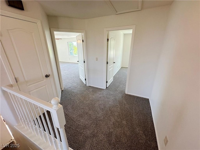 corridor with dark carpet, baseboards, and an upstairs landing