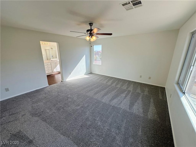 interior space with baseboards, visible vents, dark carpet, and ceiling fan
