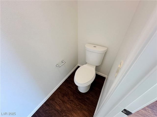 bathroom featuring baseboards, wood finished floors, and toilet