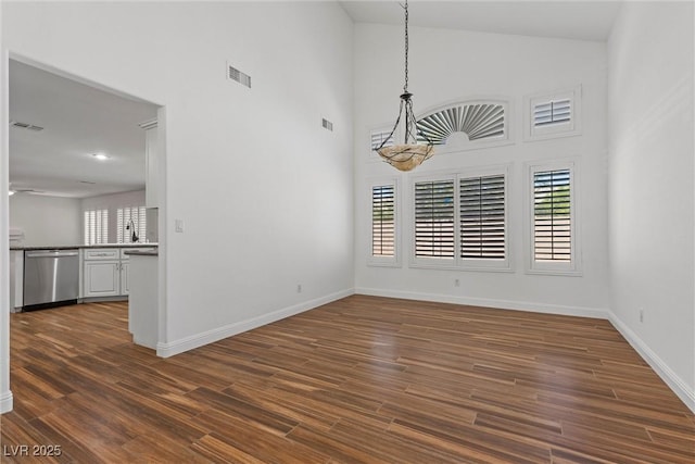 283 Grand Olympia Dr, Henderson, NV 89012 - unfurnished dining area featuring dark wood-style floors, high vaulted ceiling, and baseboards