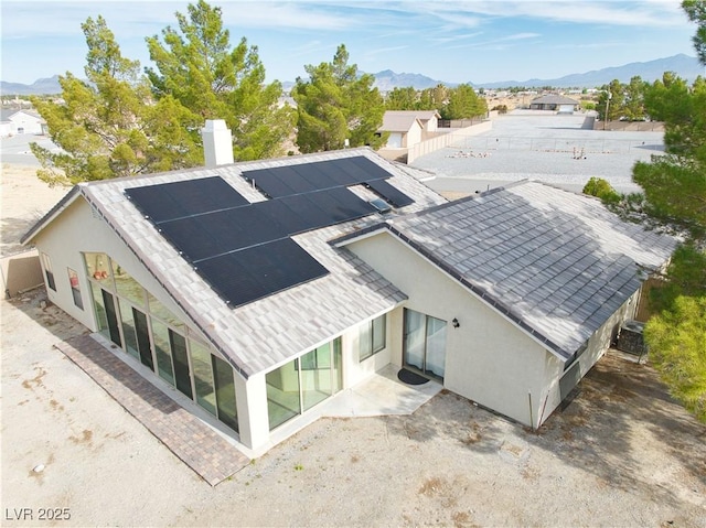 151 Hornet St, Pahrump, NV 89048 - rear view of house featuring a mountain view, stucco siding, a chimney, and solar panels