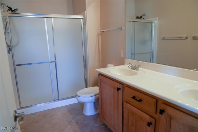 full bath with tile patterned floors, double vanity, toilet, a sink, and a stall shower
