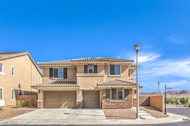 mediterranean / spanish house with driveway, stone siding, fence, a mountain view, and a garage