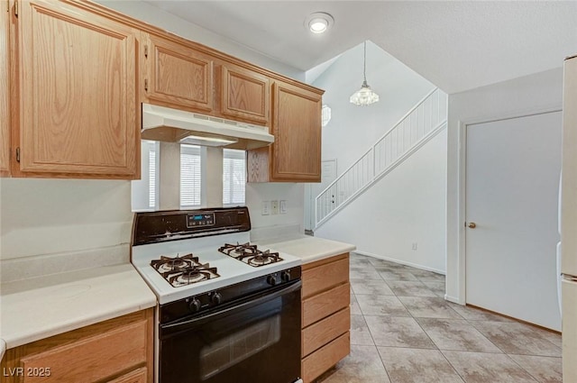 kitchen with light tile patterned floors, light countertops, gas range oven, under cabinet range hood, and decorative light fixtures
