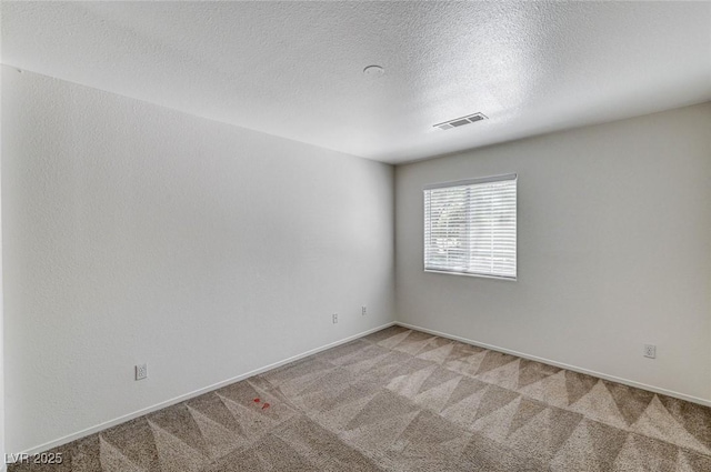 empty room with light carpet, a textured ceiling, visible vents, and baseboards