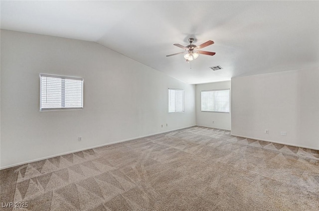 spare room featuring vaulted ceiling, visible vents, a ceiling fan, and light colored carpet