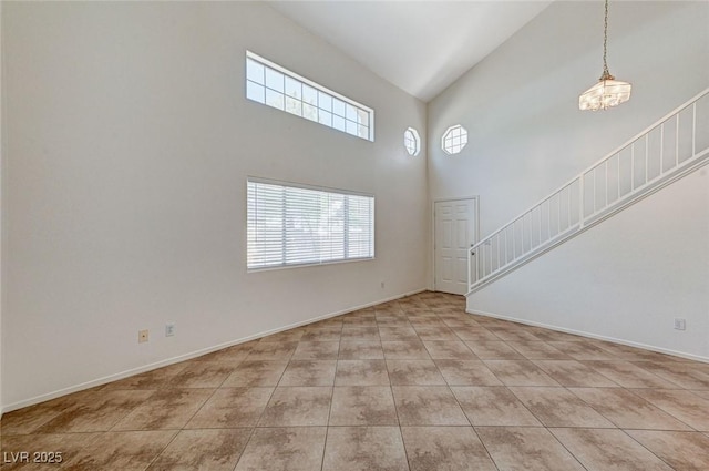 unfurnished living room with tile patterned flooring, baseboards, high vaulted ceiling, and stairs