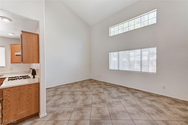 unfurnished dining area with baseboards, high vaulted ceiling, and light tile patterned floors