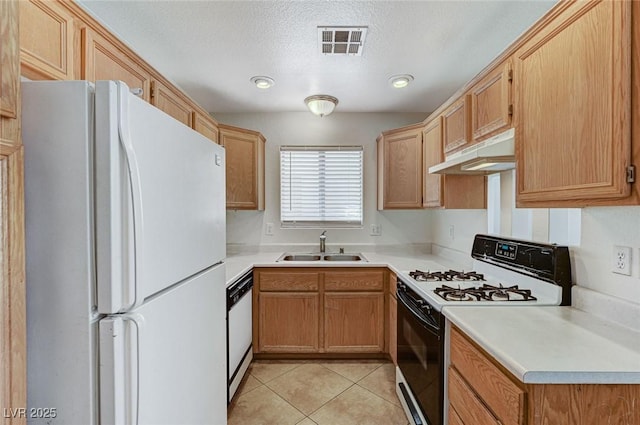 kitchen featuring under cabinet range hood, visible vents, a sink, light tile patterned floors, and white appliances