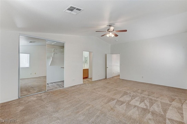 unfurnished bedroom with a ceiling fan, light carpet, ensuite bath, lofted ceiling, and visible vents