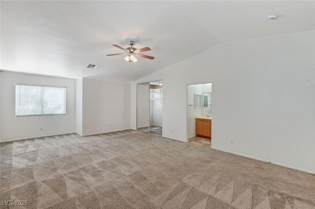 interior space with lofted ceiling, a ceiling fan, visible vents, and light colored carpet