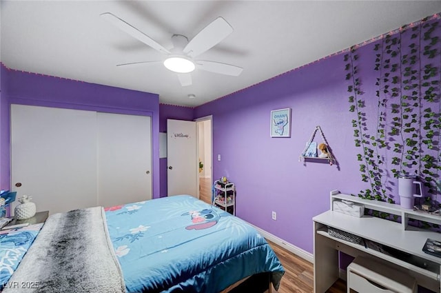 bedroom with ceiling fan, baseboards, wood finished floors, and a closet