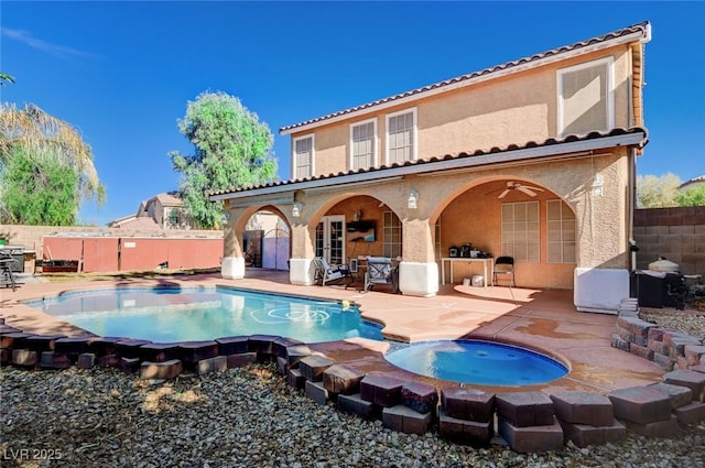 rear view of property with a tiled roof, a fenced backyard, a patio area, an in ground hot tub, and stucco siding