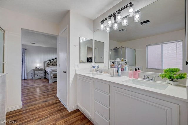 ensuite bathroom featuring a shower with door, wood finished floors, visible vents, a sink, and ensuite bath