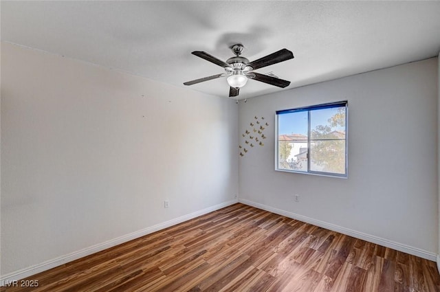 spare room featuring wood finished floors, a ceiling fan, and baseboards