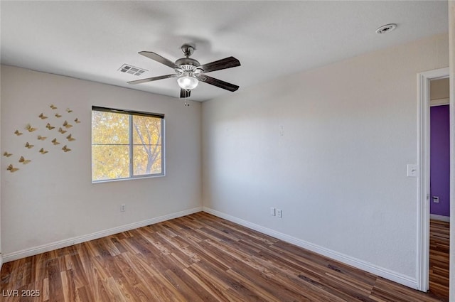 spare room featuring wood finished floors, visible vents, a ceiling fan, and baseboards