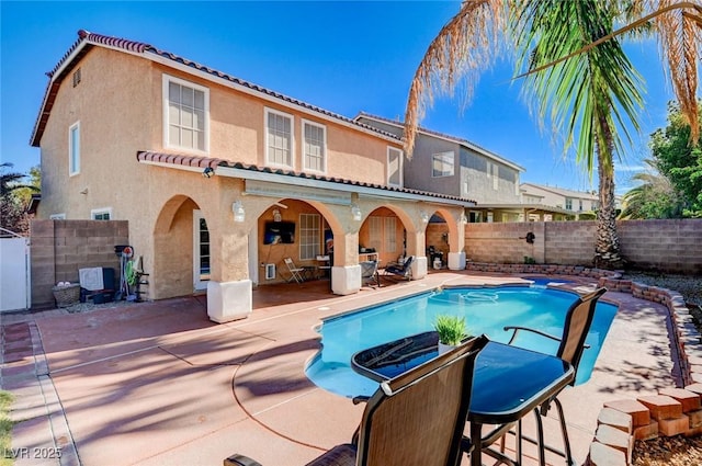 rear view of house with a fenced in pool, a fenced backyard, a tiled roof, stucco siding, and a patio