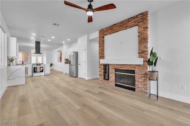10200 Wood Work Ln, Las Vegas, NV 89135 - unfurnished living room featuring a stone fireplace, a ceiling fan, baseboards, light wood-style flooring, and recessed lighting