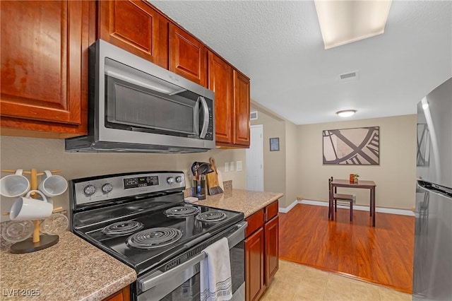 kitchen featuring baseboards, visible vents, brown cabinets, and appliances with stainless steel finishes