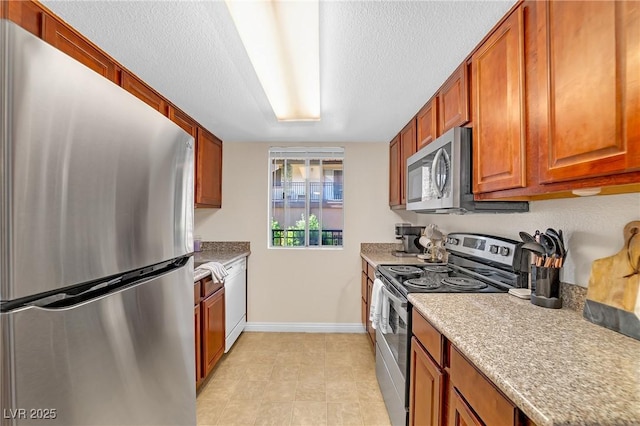 kitchen with brown cabinetry, baseboards, appliances with stainless steel finishes, and light countertops