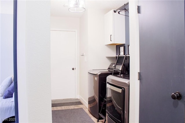 6198 Pinewood Ave, Las Vegas, NV 89103 - washroom with baseboards, cabinet space, washing machine and clothes dryer, and light wood finished floors