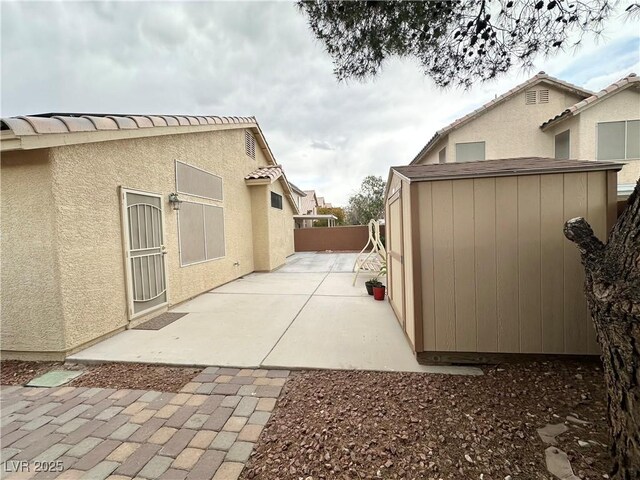 4484 Warbonnet Way, Las Vegas, NV 89147 - view of side of property with a storage unit, stucco siding, an outdoor structure, a fenced backyard, and a patio area