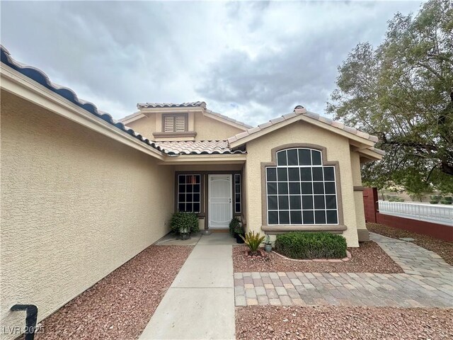 4484 Warbonnet Way, Las Vegas, NV 89147 - property entrance with a tile roof, fence, and stucco siding