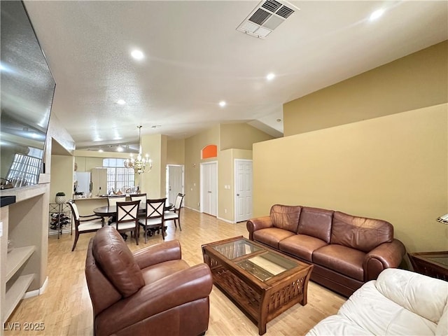 4484 Warbonnet Way, Las Vegas, NV 89147 - living room with vaulted ceiling, light wood-style floors, visible vents, and a notable chandelier