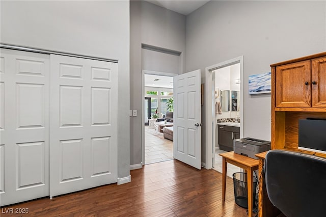 office with baseboards, a high ceiling, and dark wood-style flooring