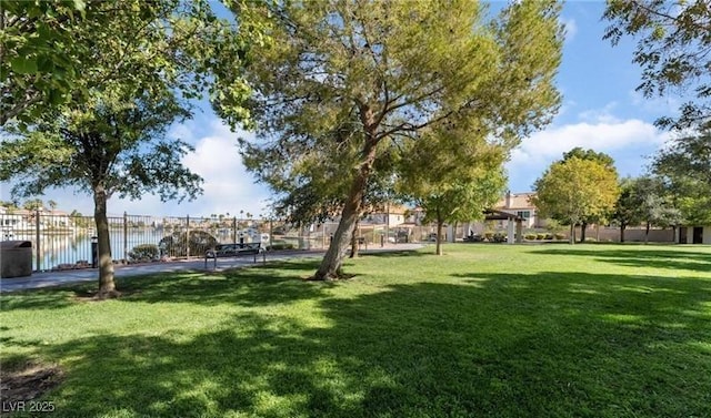 view of property's community with a lawn, fence, and a water view