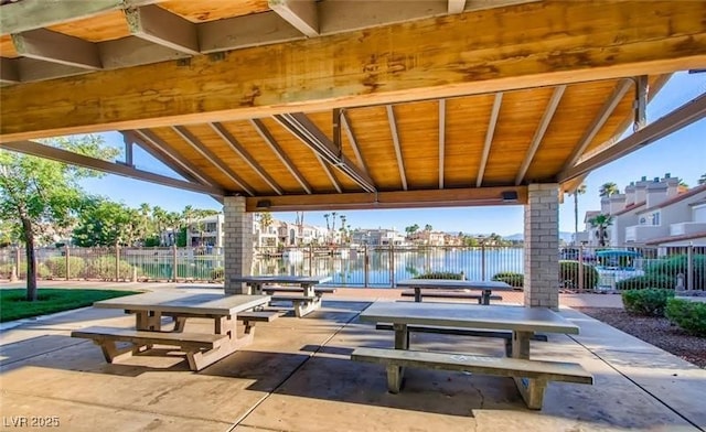 view of home's community with a water view, outdoor dining area, a patio, and fence