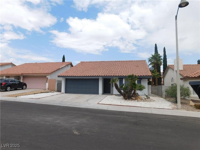 mediterranean / spanish home with an attached garage, a tiled roof, and driveway