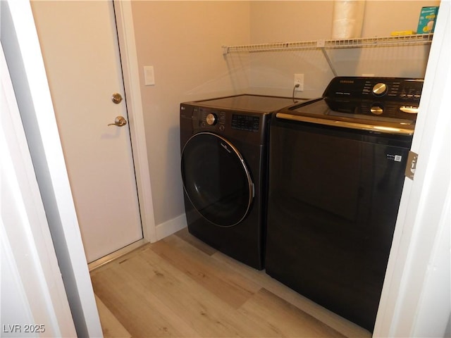 clothes washing area featuring washer and dryer, baseboards, light wood finished floors, and laundry area