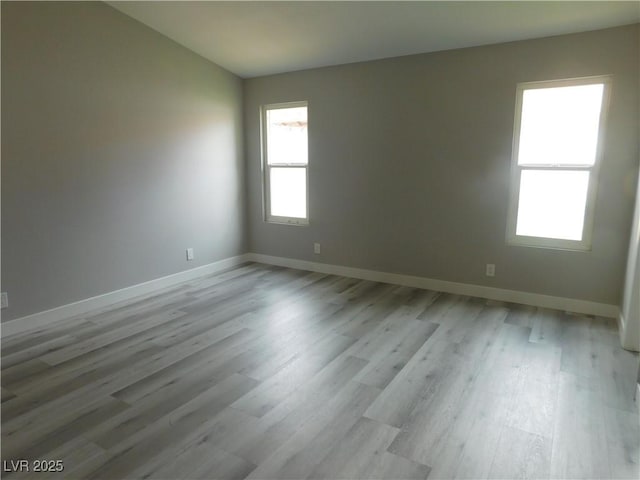 empty room featuring light wood finished floors and baseboards