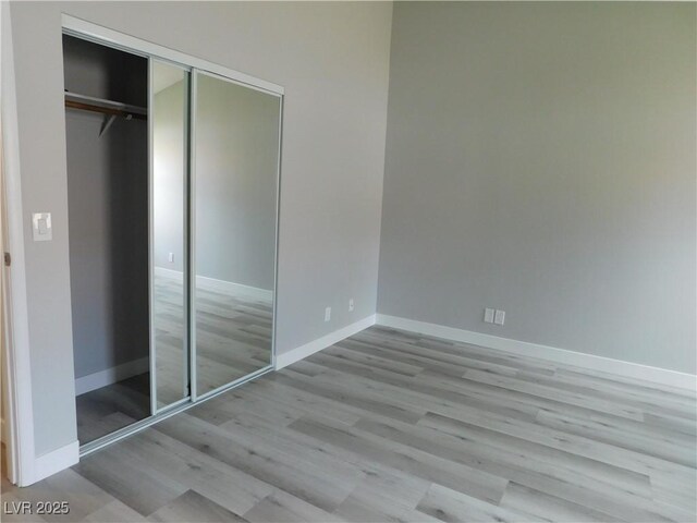 unfurnished bedroom with baseboards, wood finished floors, and a closet