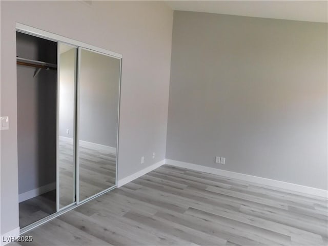 unfurnished bedroom featuring baseboards, wood finished floors, and a closet