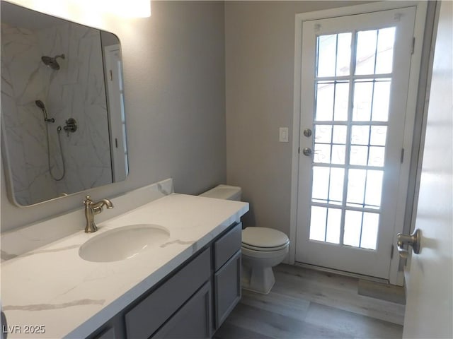 bathroom with toilet, vanity, a marble finish shower, and plenty of natural light
