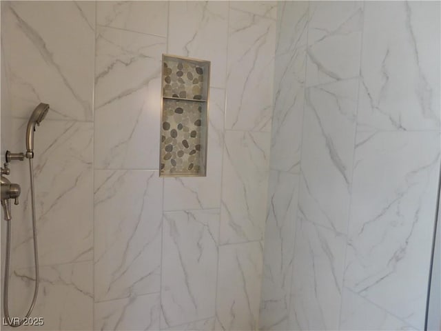 interior details featuring a marble finish shower