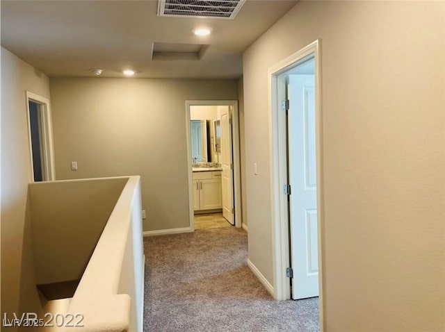 7892 W Shelbourne Ave, Las Vegas, NV 89113 - hallway with attic access, light carpet, baseboards, visible vents, and an upstairs landing