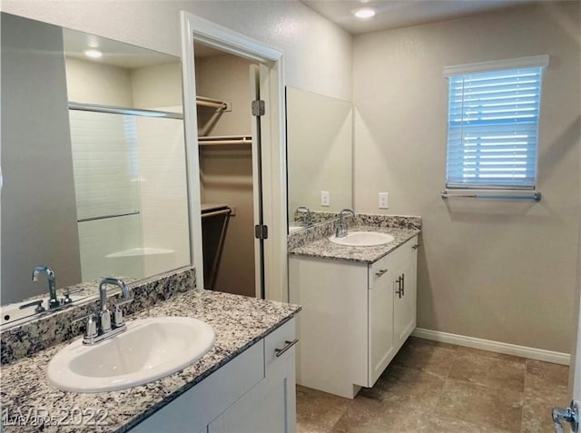 7892 W Shelbourne Ave, Las Vegas, NV 89113 - bathroom featuring two vanities, an enclosed shower, baseboards, and a sink