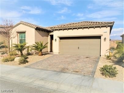 mediterranean / spanish-style home featuring a garage, driveway, a tiled roof, and stucco siding