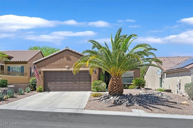 view of front of property with stucco siding, driveway, a tiled roof, and a garage