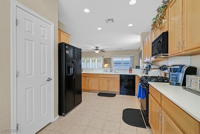 kitchen with a sink, visible vents, light brown cabinets, light countertops, and black appliances